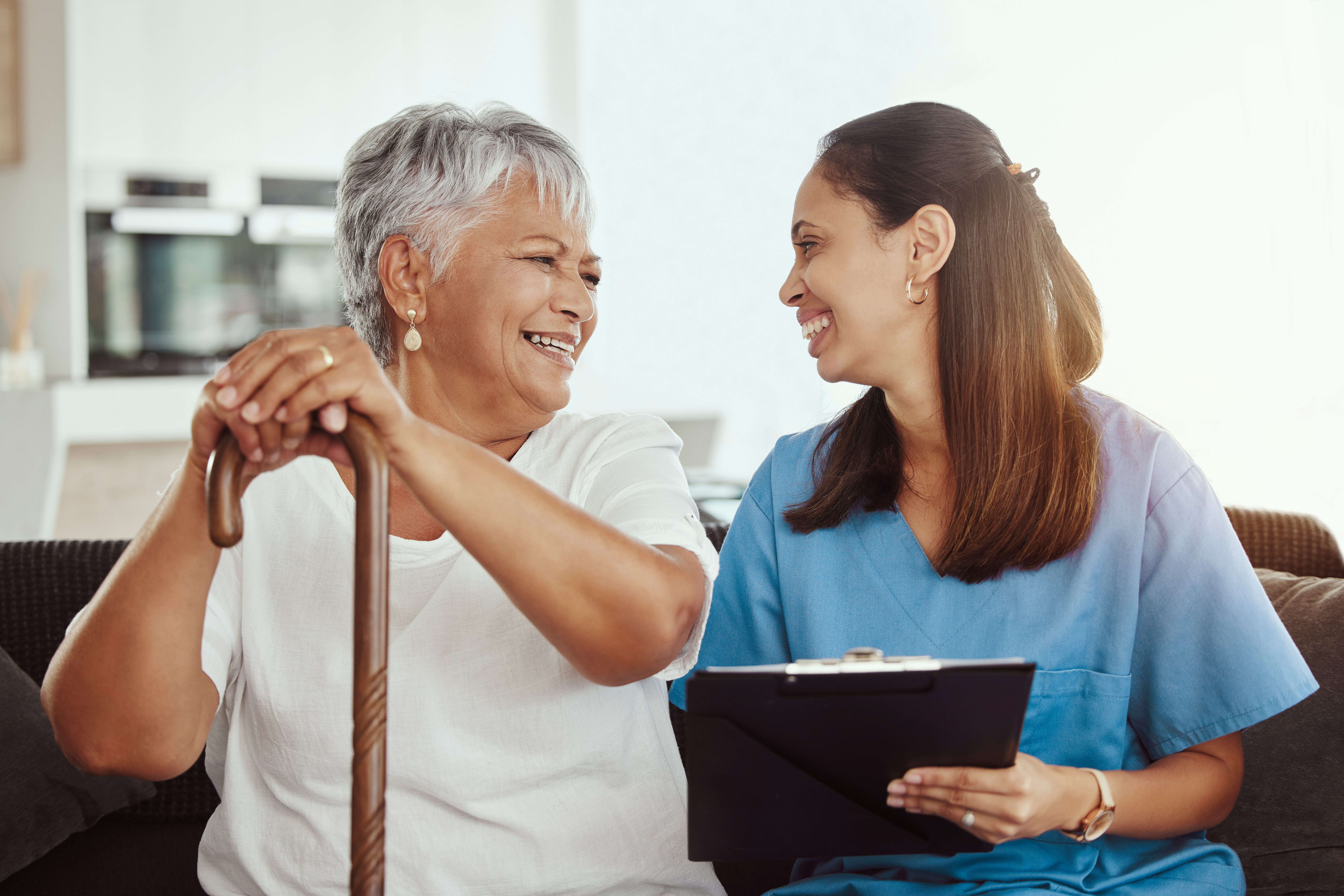 Senior care, healthcare insurance and caregiver woman sitting with elderly woman patient laughing a